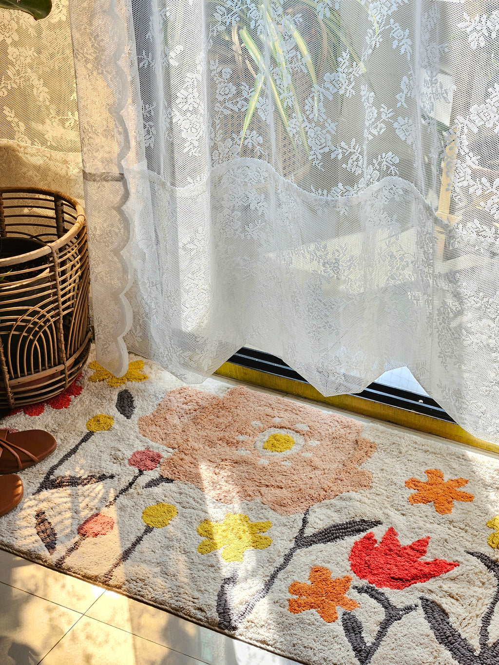 Side-angle of the Blossom Trail Rug styled in a cozy, boho-inspired living room with natural light and rattan furniture.

