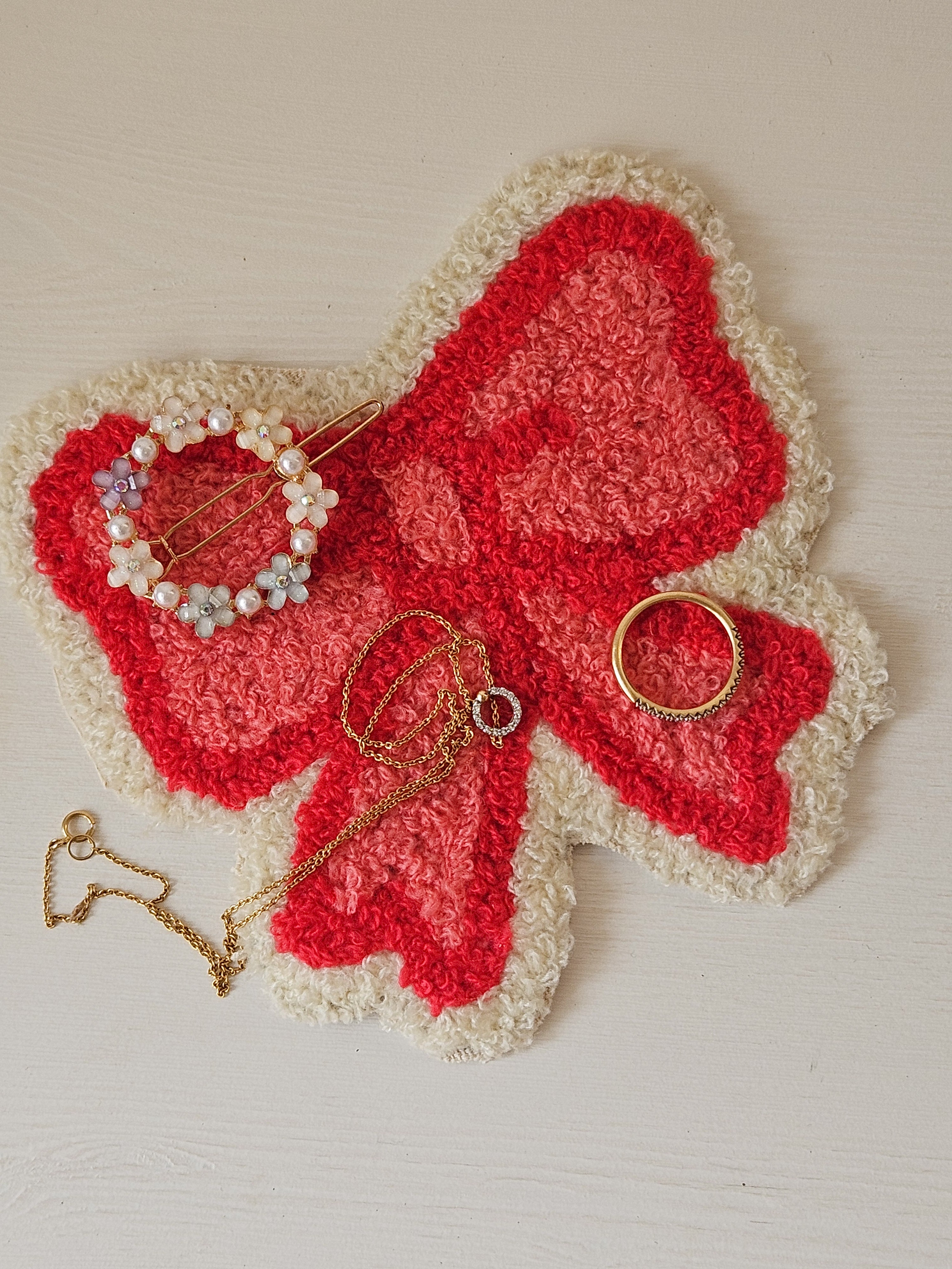 Flat lay of a boho cotton mug rug in beige and pink, styled with a mug and table accessories

