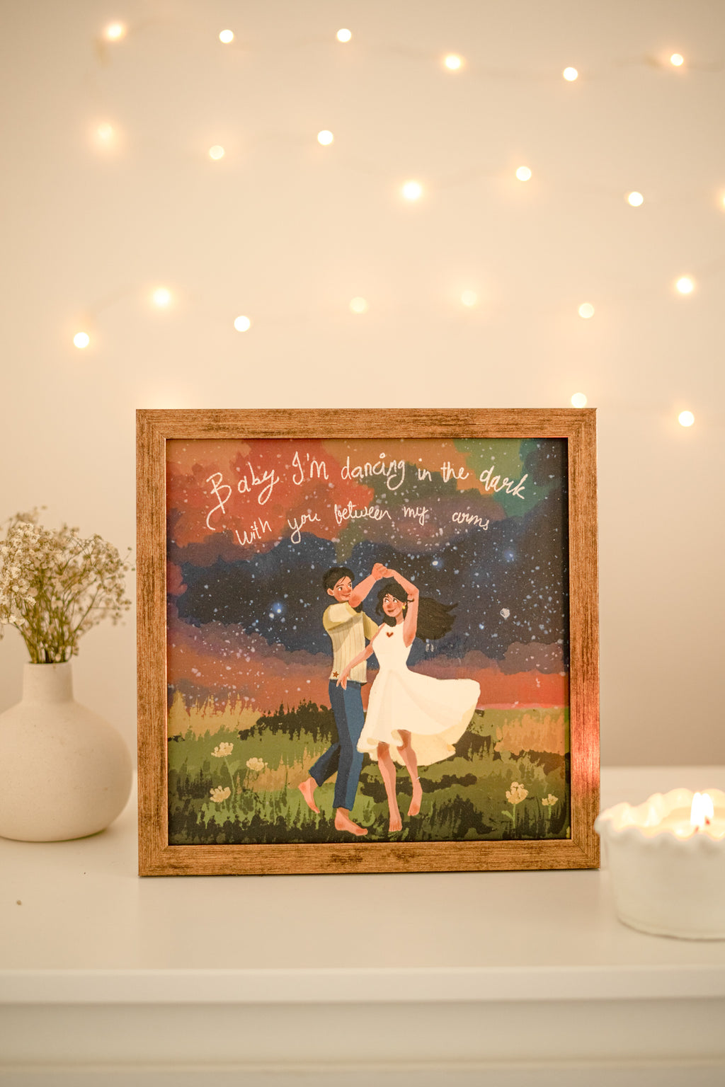 Framed dance art styled on a minimalist wall above a wooden console with warm lighting and modern decor.

