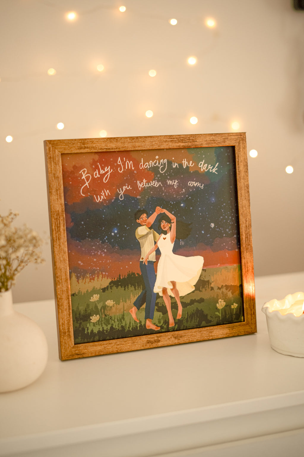 Framed print displayed on a white wall above a wooden console table, styled with warm-toned decor and soft lighting for a cozy, contemporary look.

