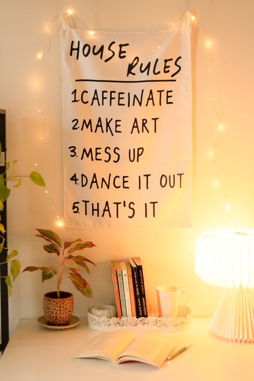 Frontal view of “The Boho Code” tapestry hanging on a neutral wall, featuring boho-inspired typography and colorful design.

