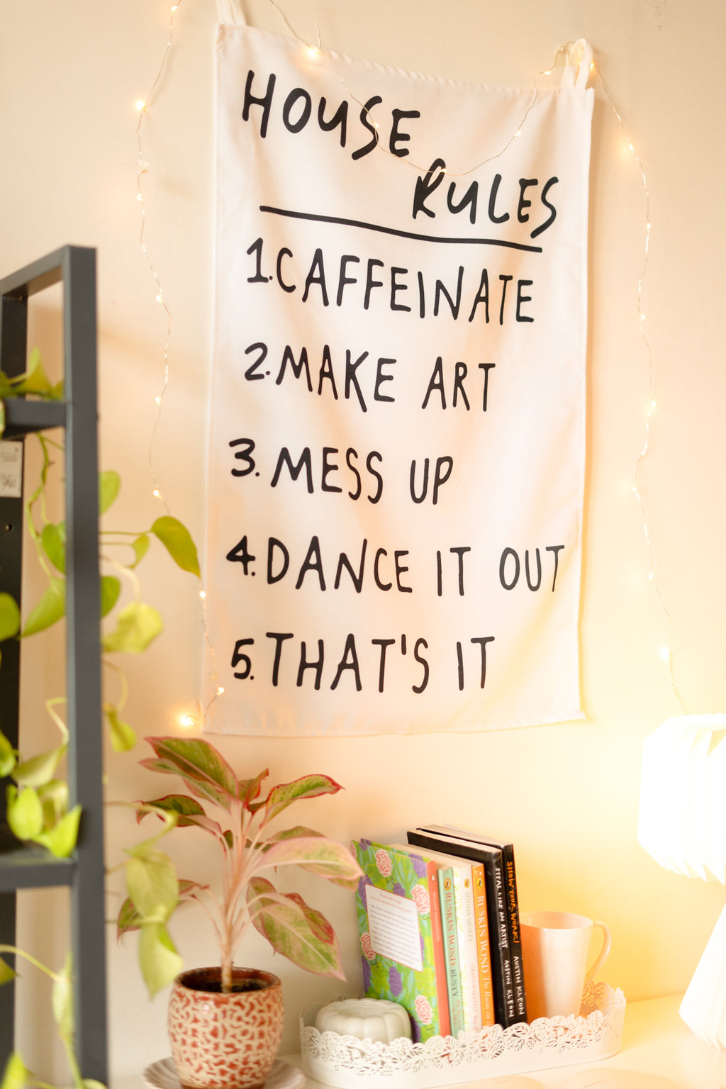 Side angle of “The Boho Code” tapestry displayed above a wooden console with potted plants and bohemian décor.

