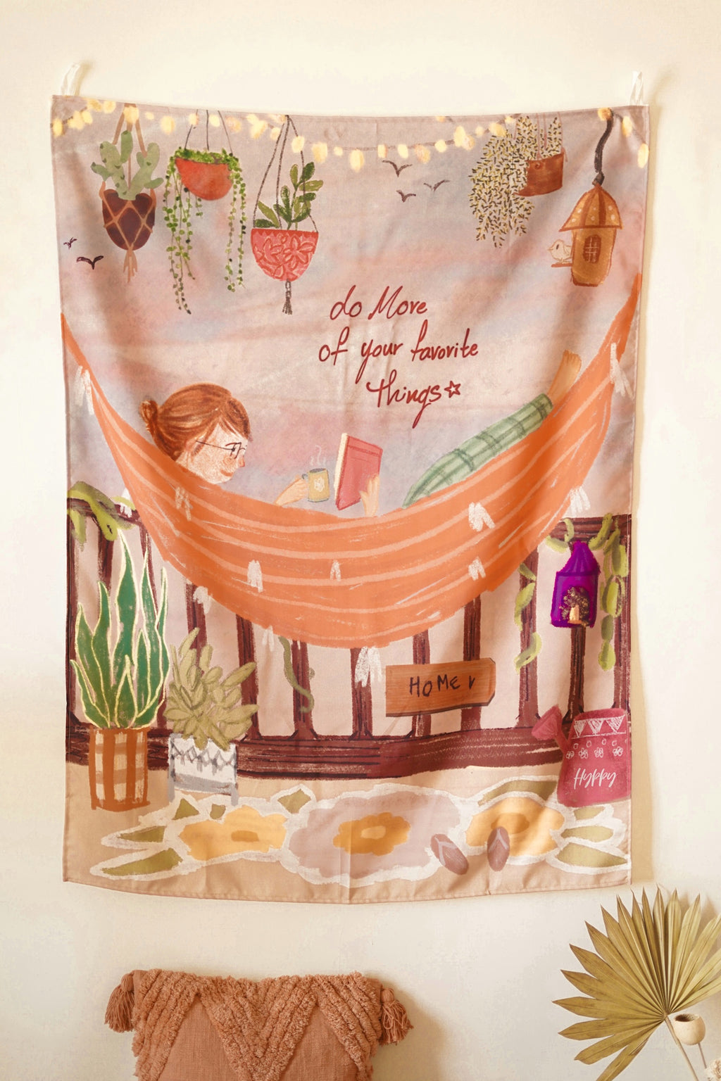 Beige cotton wall tapestry with minimalist black illustrations of cozy daily objects, displayed against a plain white background.

