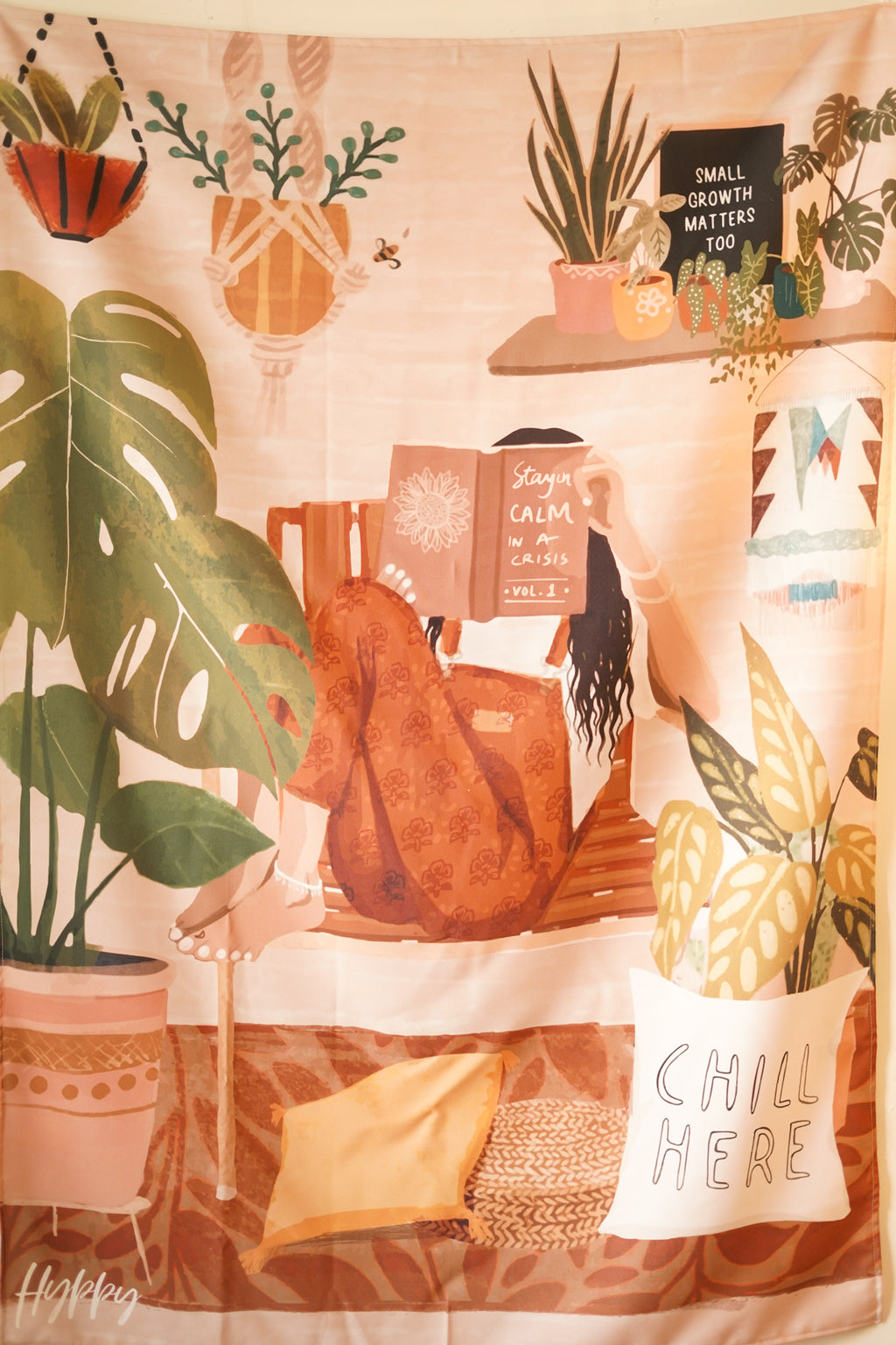 Close-up of the Boho Tapestry's design, highlighting the warm color palette and bohemian elements like indoor plants and stacked books.


