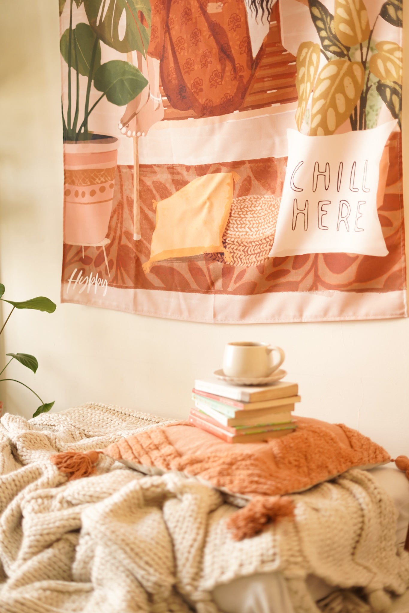 Close-up of the Boho Tapestry's design, highlighting the warm color palette and bohemian elements like indoor plants and stacked books.

