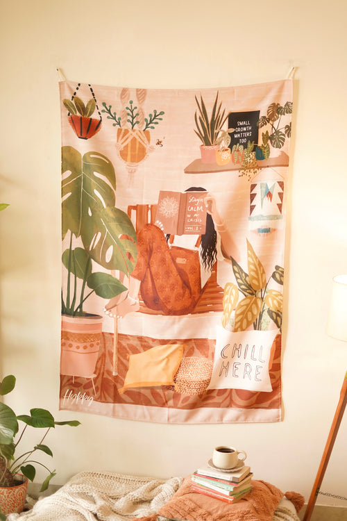 Full view of the Boho Tapestry hanging on a neutral-toned wall, featuring a cozy reading nook with plants, books, and a "Chill Here" cushion image.

