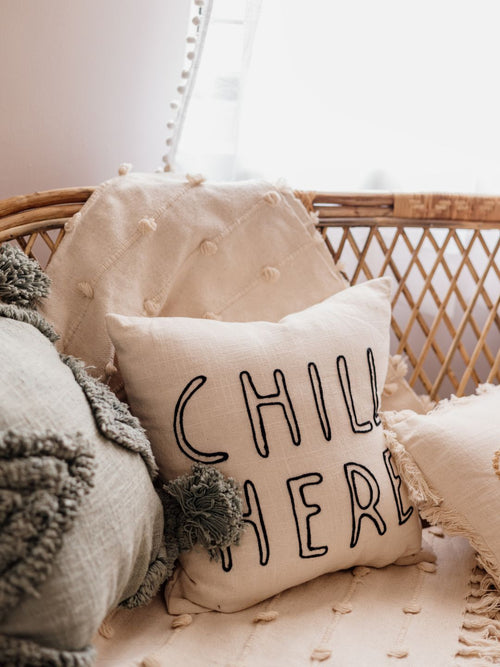 Square cotton pillow with “Chill Here” embroidered in brown on a beige base — cozy and minimal for modern homes.

